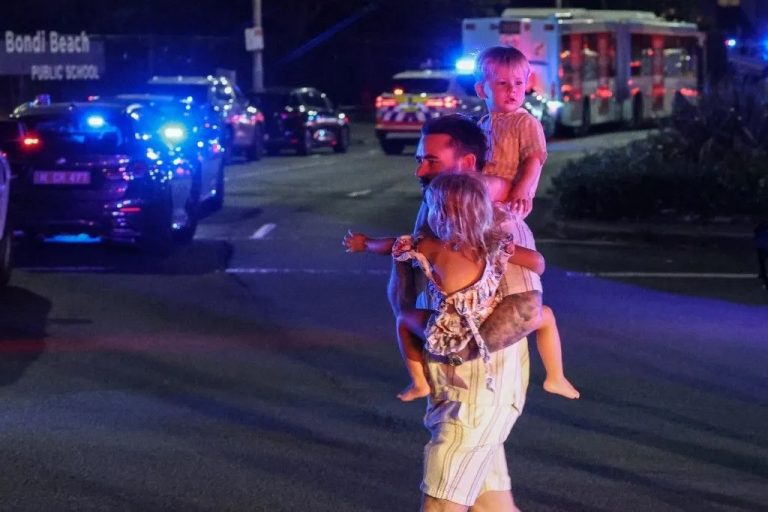 Un homme portant deux jeunes enfants, le 14 décembre 2025 après l'attentat