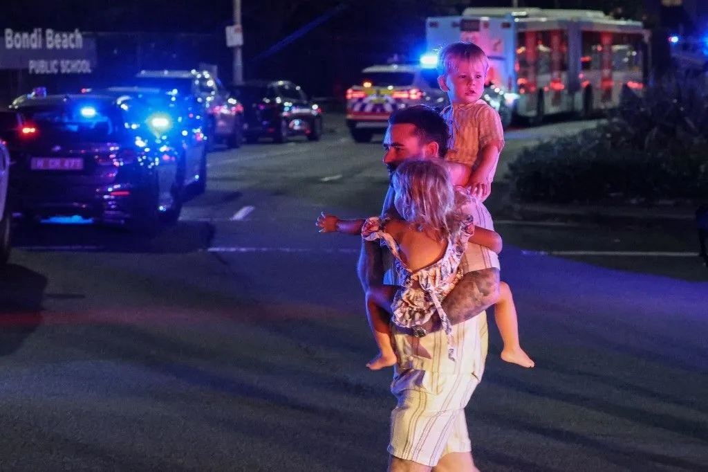 Un homme portant deux jeunes enfants, le 14 décembre 2025 après l'attentat
